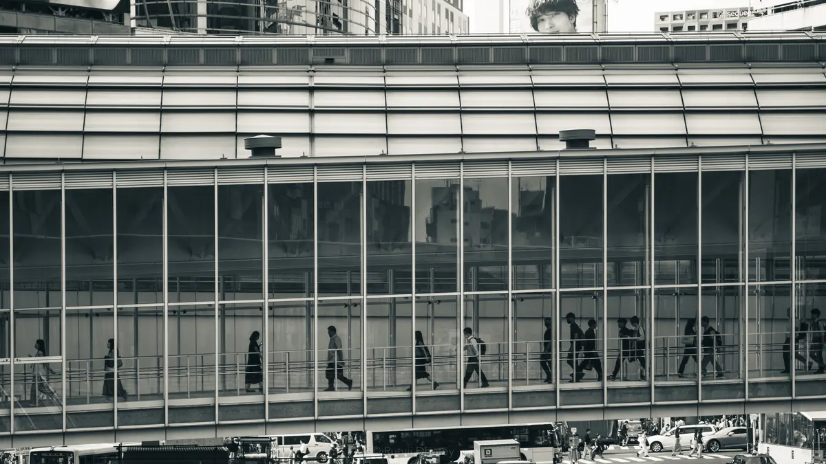 Commuters crossing a glass walkway at Shinjuku station, Tokyo