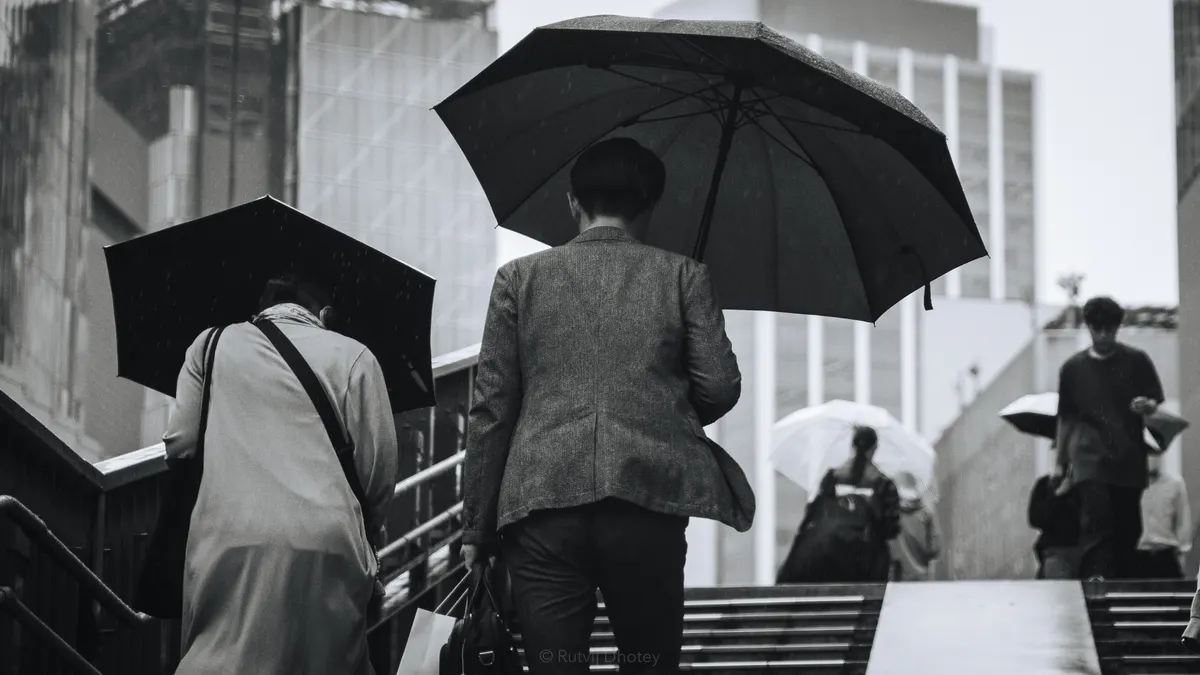 A man with an umbrella on wet steps, in black and white