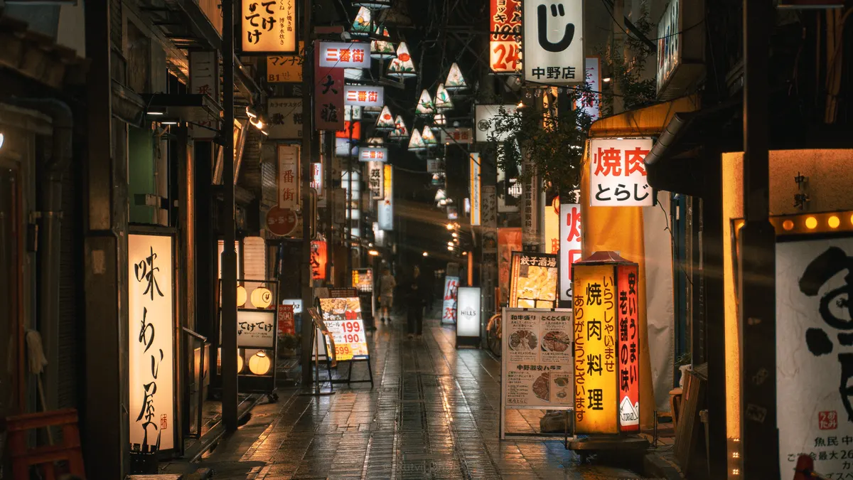 A narrow alley of lit signage after rain
