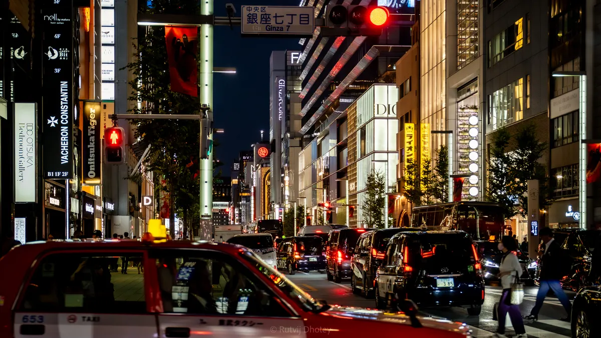 A red taxi waiting at a crossing after dark
