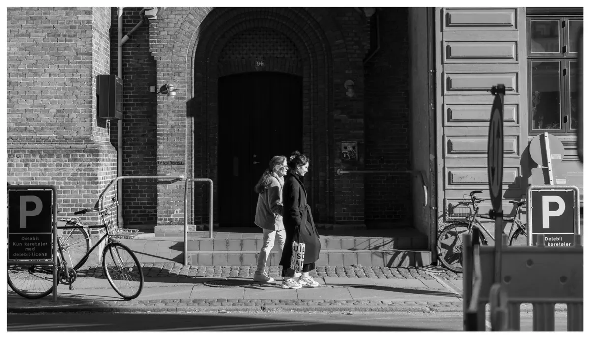 A bicycle leaning against a building wall, in black and white