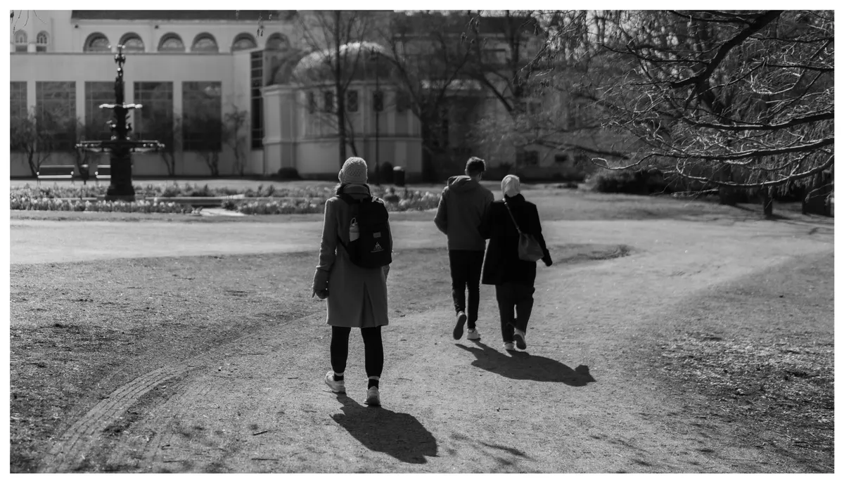 Figures walking a path through a park, in black and white