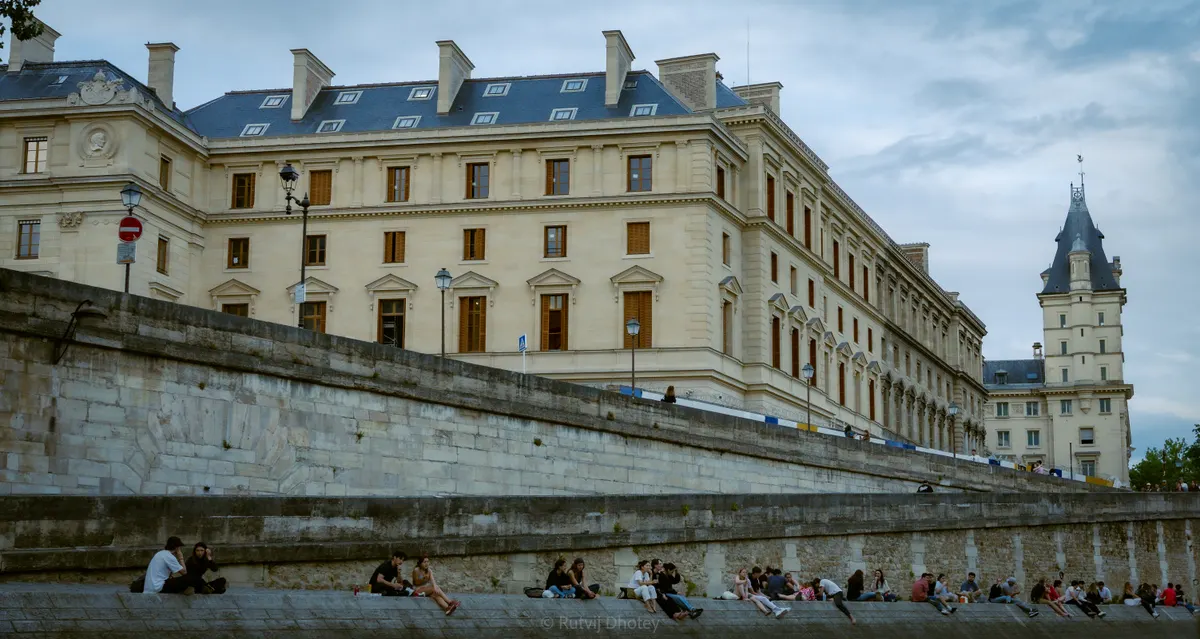 People sitting on the steps below a Haussmann facade