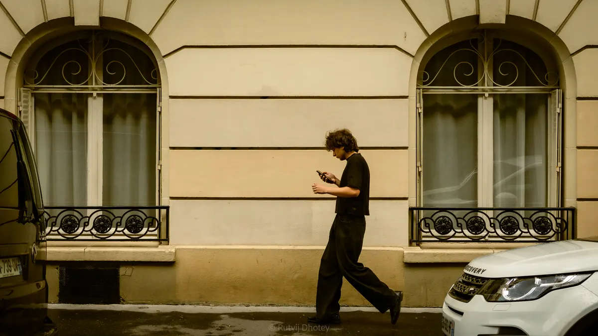 A figure walking past an ornate cream facade